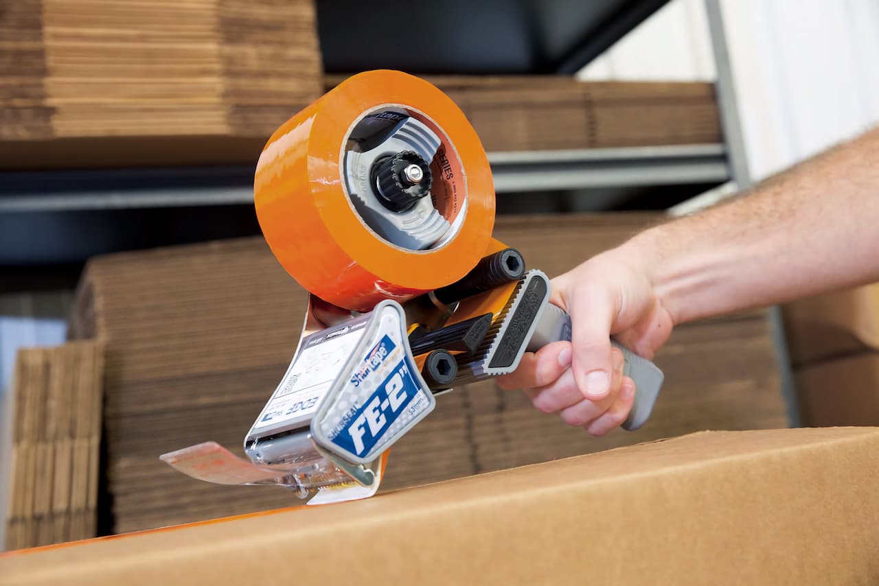 Persona realizando embalaje de productos con cintas Hot Melt