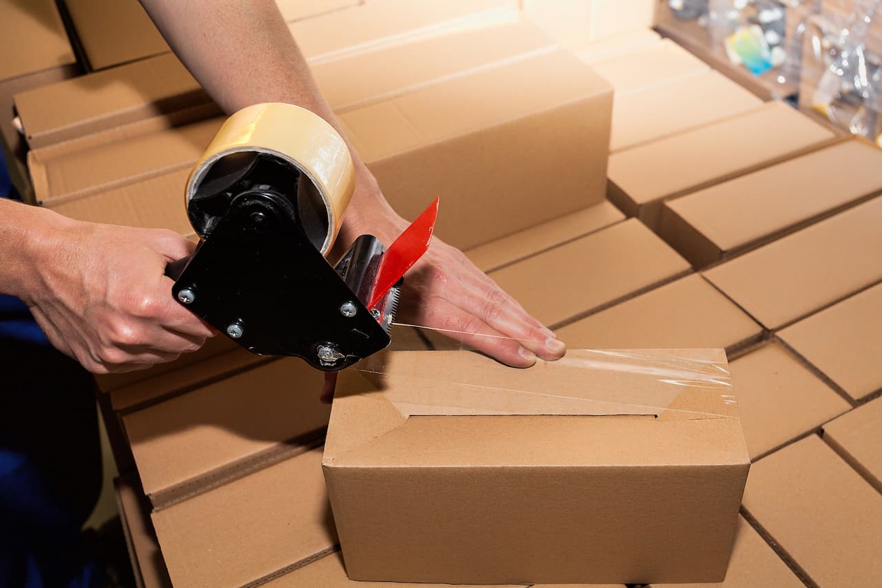 Persona realizando embalaje de productos con cintas Hot Melt